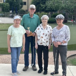 people posing with a trophy and golf putters