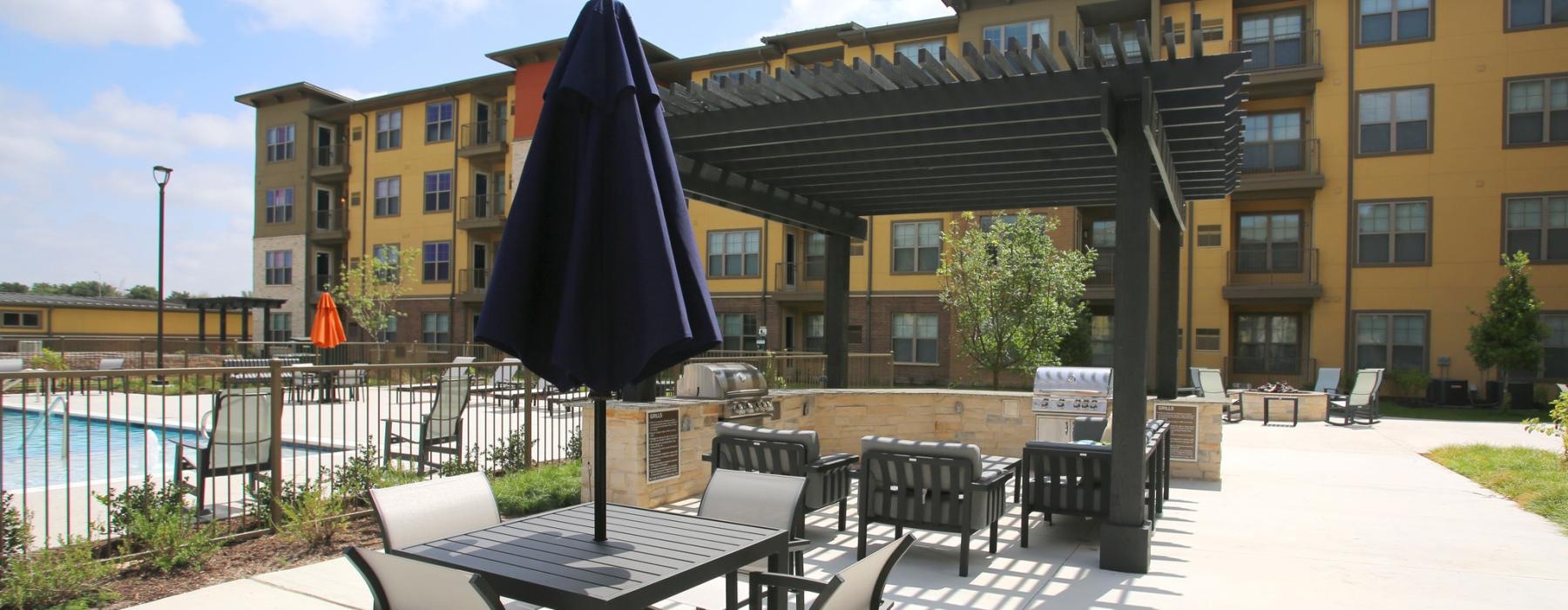 a patio with tables and chairs and umbrellas by a building
